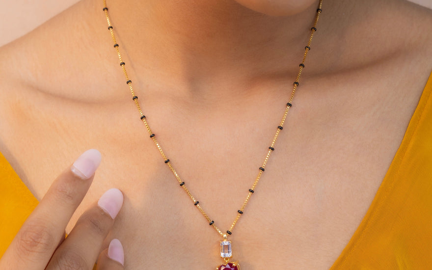 a beautiful women in yellow dress wearing pink ruby stone chain mangalsutra from stone story brand