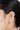 A model wearing circular stud earrings featuring bezel-set peridot gemstones in 925 sterling silver with matte gold, polished gold, and rhodium-plated finishes.