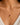 A close-up of a model's neck wearing a delicate 925 sterling silver 18k gold plated chain necklace with a small bow-shaped pendant featuring a central round pink gemstone.