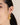 A model wearing Heart-shaped hoop earrings featuring bezel-set amethyst gemstones in 925 sterling silver with 18K gold plating.