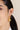 A model wearing Heart-shaped hoop earrings featuring bezel-set amethyst gemstones in 925 sterling silver with 18K gold plating.