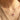 A close-up of a person wearing a delicate 925 sterling silver necklace with a bow-shaped pendant featuring a small pink gemstone at the top, paired with a beige knit sweater