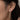 A close-up of a model's ear wearing 925 sterling silver rhodium plated drop earring with five clear round-cut stones.
