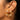 A close-up of a model's ear wearing  925 sterling silver 18K Gold-plated statement stud earrings featuring clear quartz gemstones in an intricate circular openwork design alongside a small silver stud earring.
