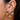A close-up of a person's ear showing a 925 sterling silver earrings with five green oval stones, alongside other gold ear cuff with green stone