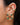 A close-up of a person's ear showing a 925 sterling silver earrings with five green oval stones, alongside other gold ear cuff with green stone
